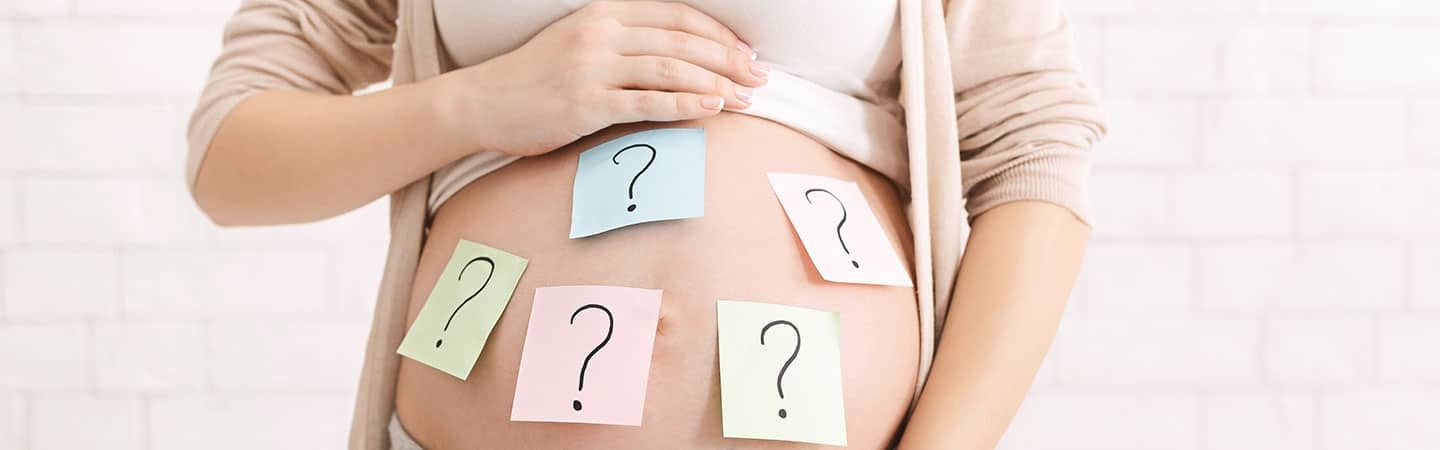 Bauch einer schwangeren Frau mit Fragezeichen
